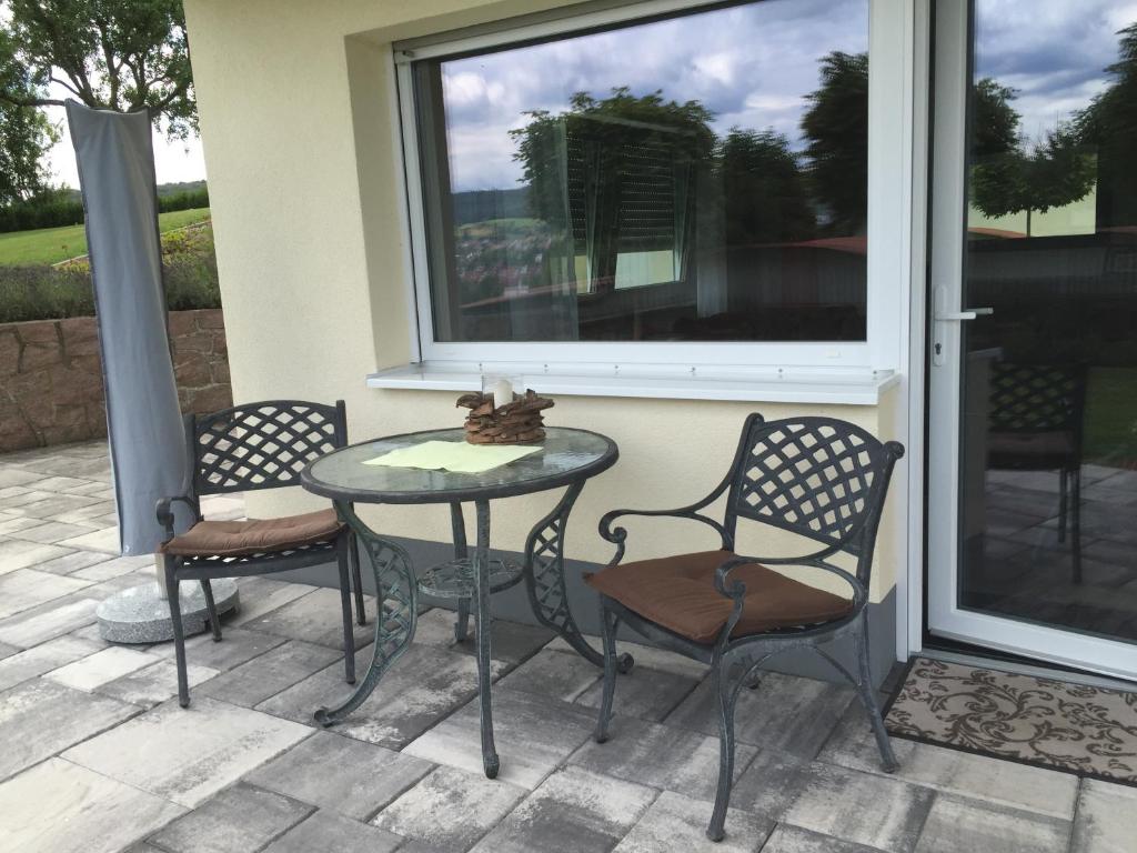 a patio with a table and chairs and a window at Ferienwohnung Am Galgenberg in Michelstadt