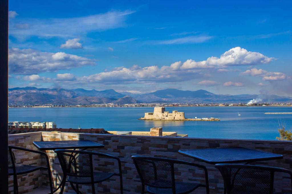 a patio with tables and chairs and a view of the water at Bonne Nuit Pension in Nafplio