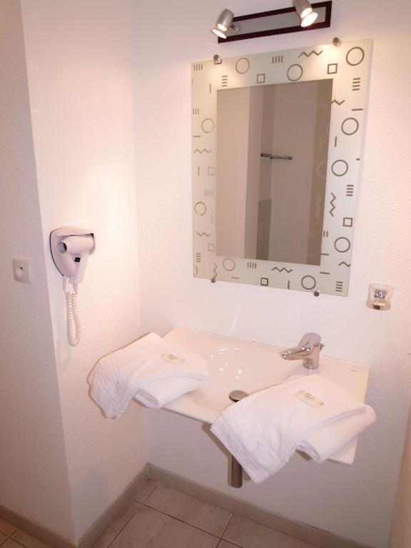 a bathroom with a sink with a mirror and towels at Village Club Thalassa in Mèze