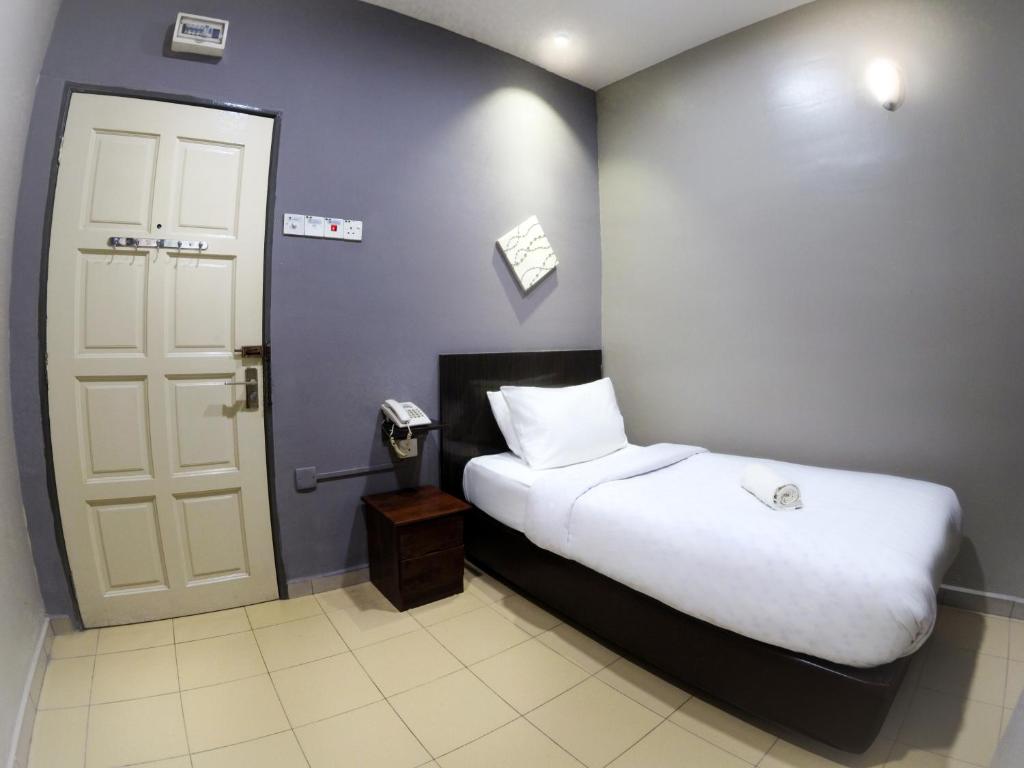 a bedroom with a bed and a phone next to a door at JV Hotel @ Bandar Tasek Mutiara in Simpang Ampat
