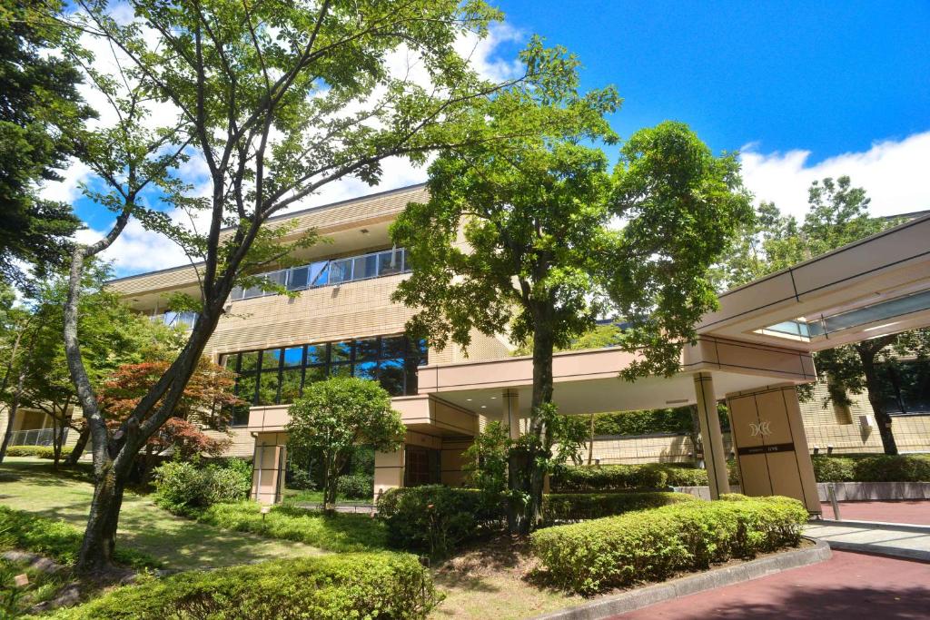 an office building with trees in front of it at Izukogen Hotel Itsutsuboshi in Ito