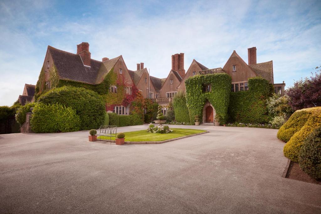 une grande maison avec du lierre sur son côté dans l'établissement Mallory Court Country House Hotel & Spa, à Leamington Spa