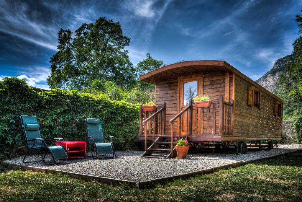 une petite maison sur une remorque avec deux chaises dans l'établissement La Roulotte, à Châtillon-en-Diois