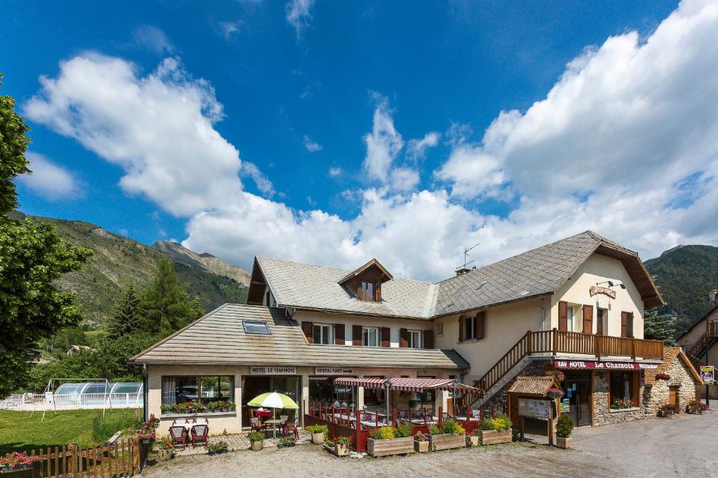 a large house with mountains in the background at Hotel restaurant Le Chamois in Ancelle