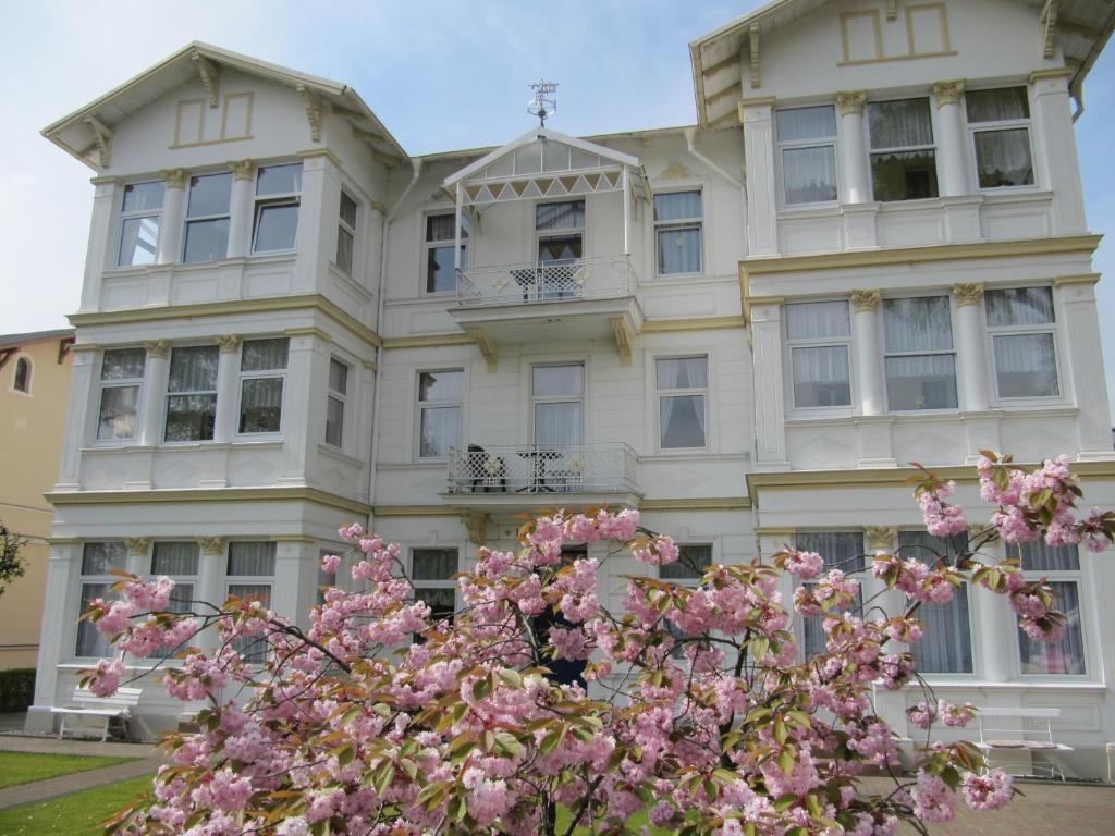un bâtiment blanc avec des fleurs roses devant lui dans l'établissement Haus Feldmann, à Ahlbeck