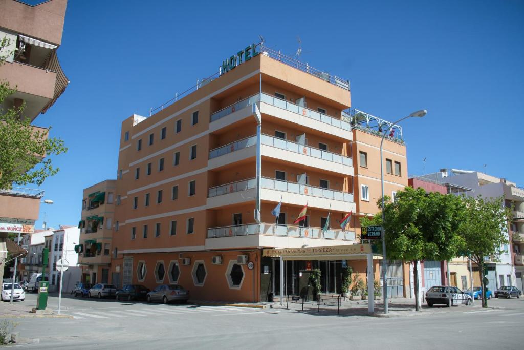 un edificio alto en una calle con coches aparcados delante en Hotel Torrezaf, en Torredelcampo
