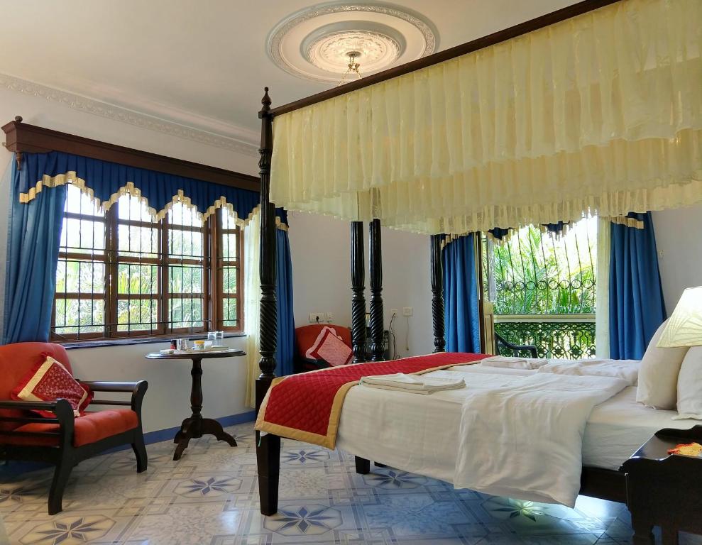 1 dormitorio con 1 cama, 1 silla y ventanas en Palm Grove Cottages - Leisure Resort, en Benaulim