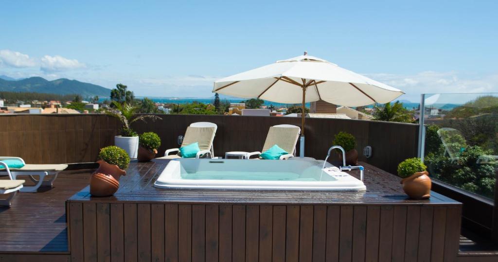 bañera de hidromasaje en un patio con sillas y sombrilla en La Plage Residence, en Garopaba