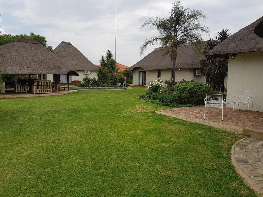 un patio con dos casas y un patio con césped en 12 On Vaal Drive Guesthouse en Vanderbijlpark