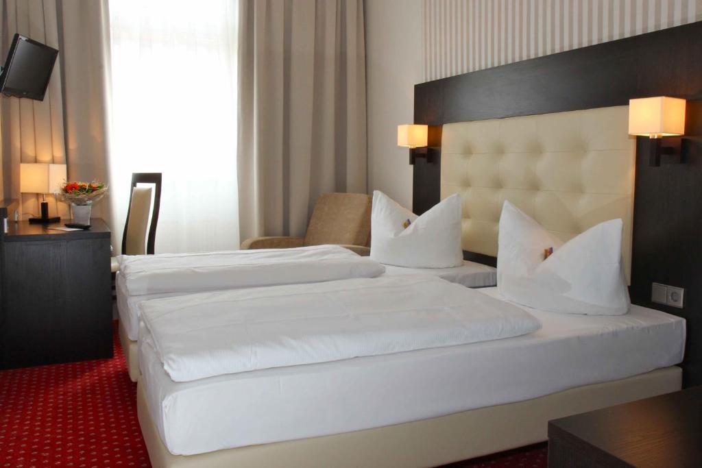 ベルリンにあるホテル ハーベスト ベルリンのホテルルーム ベッド2台 白いシーツ付