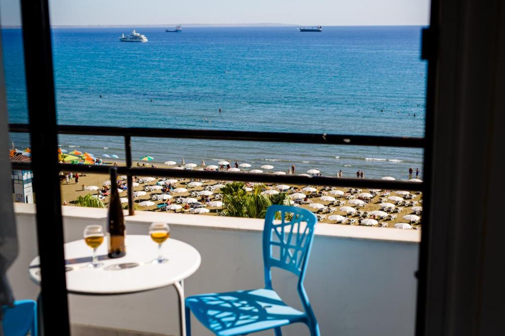 balcón con mesa y sillas y vistas a la playa en Krasas Beach Apts, en Lárnaca