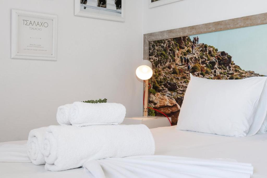 a white bed with white towels on top of it at Kaerati Apartments in Katapola