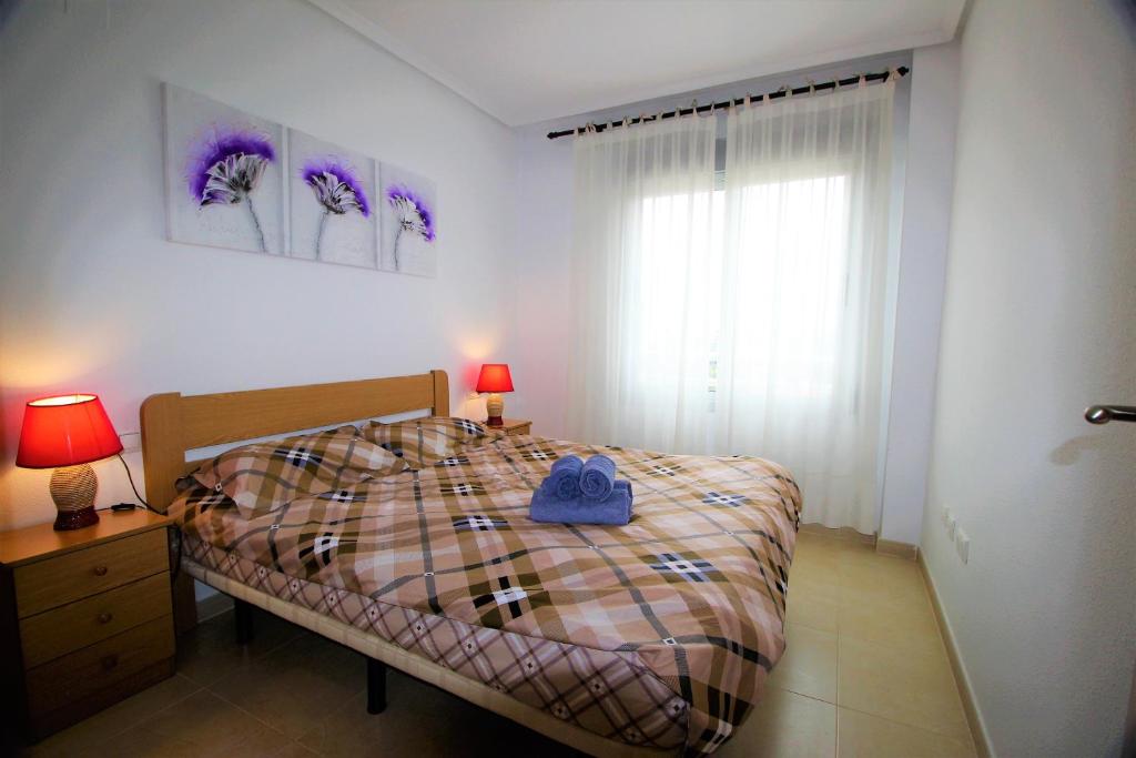 トレビエハにあるPunta Prima Homesのベッドルーム1室(ベッド1台、ランプ2つ、窓付)