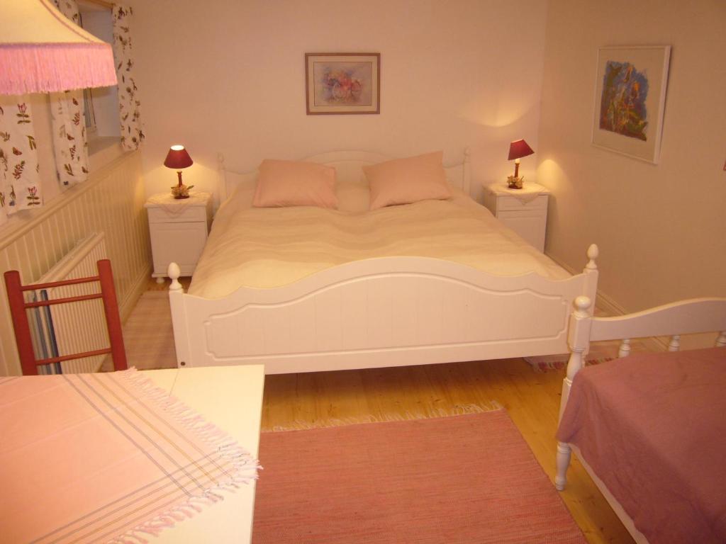 a bedroom with a white bed with two tables and two lamps at Prästmyrens Vandrarhem in Ransäter