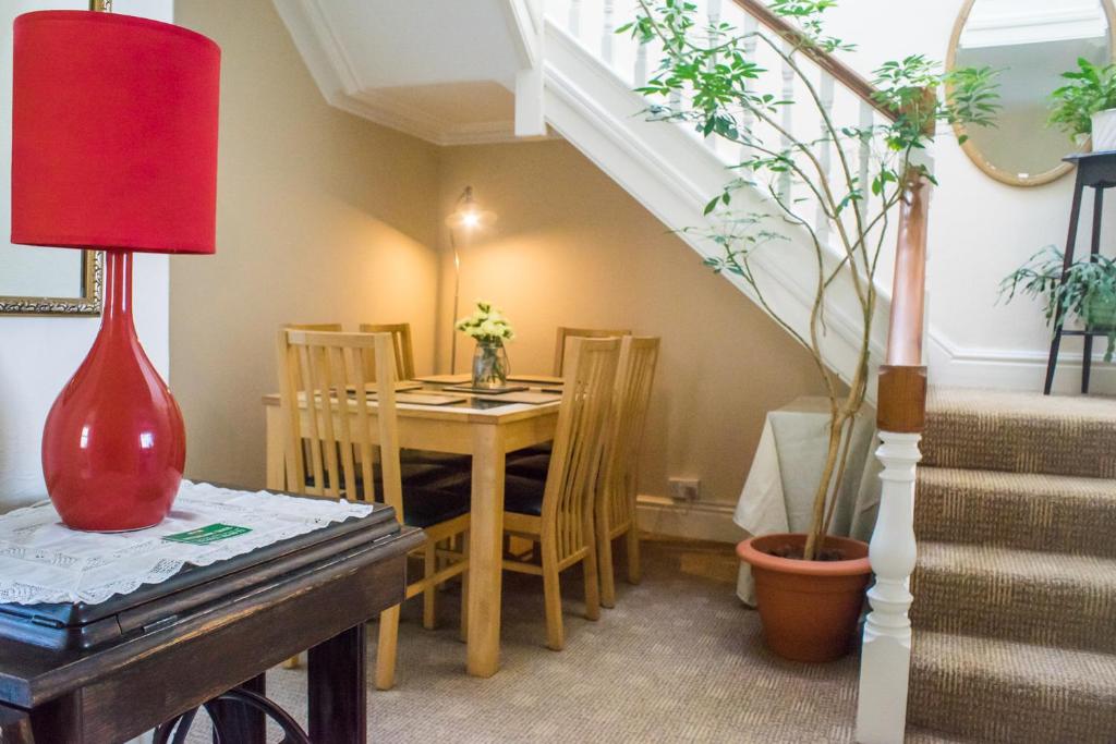a dining room with a table and a red lamp at Whitegate in Llandudno