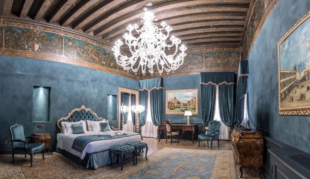 a bedroom with blue walls and a chandelier at Hotel Nani Mocenigo Palace in Venice