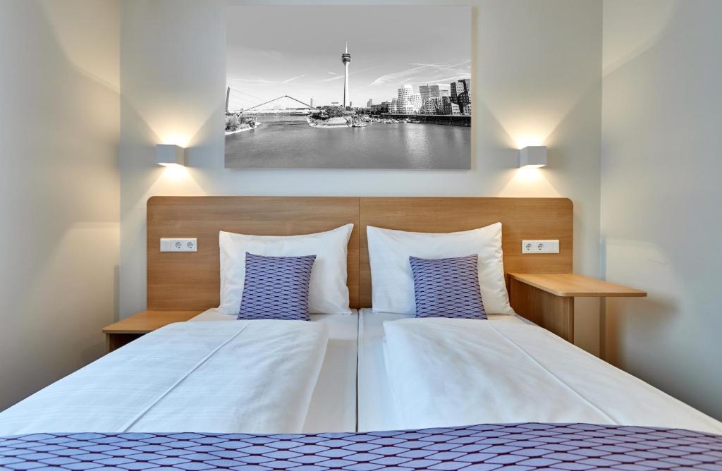 a bedroom with a bed with two blue pillows at McDreams Hotel Düsseldorf-City in Düsseldorf