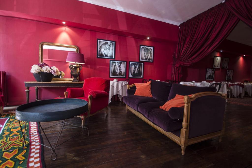 - un salon avec des murs rouges, un canapé et une table dans l'établissement Hôtel du Palais, à Angoulême