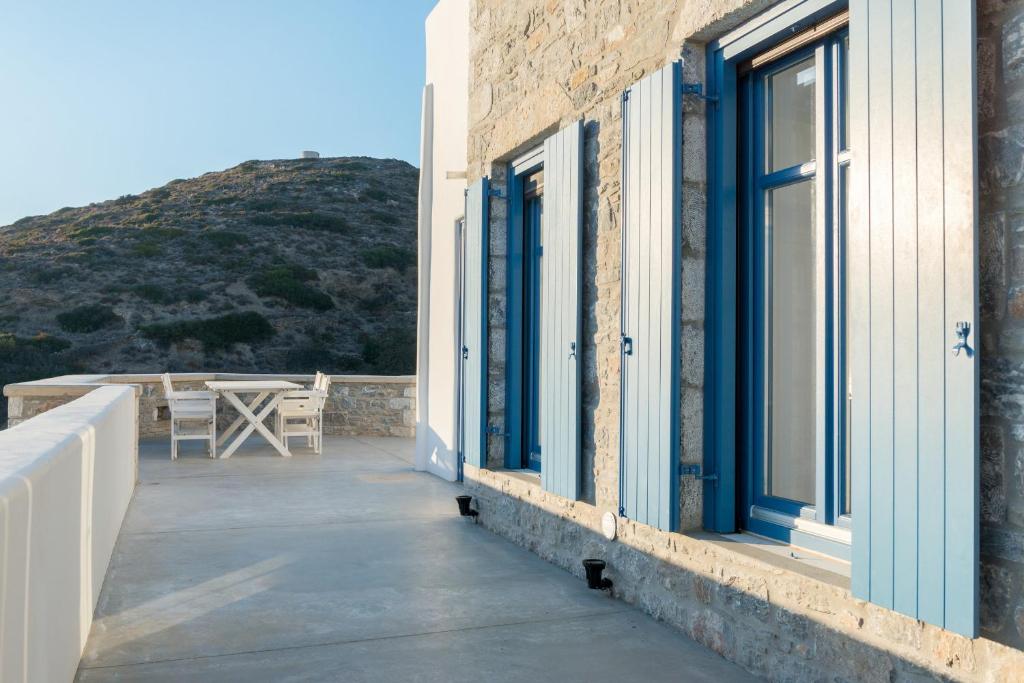 a balcony of a house with blue doors and a table at Kaerati Apartments in Katapola