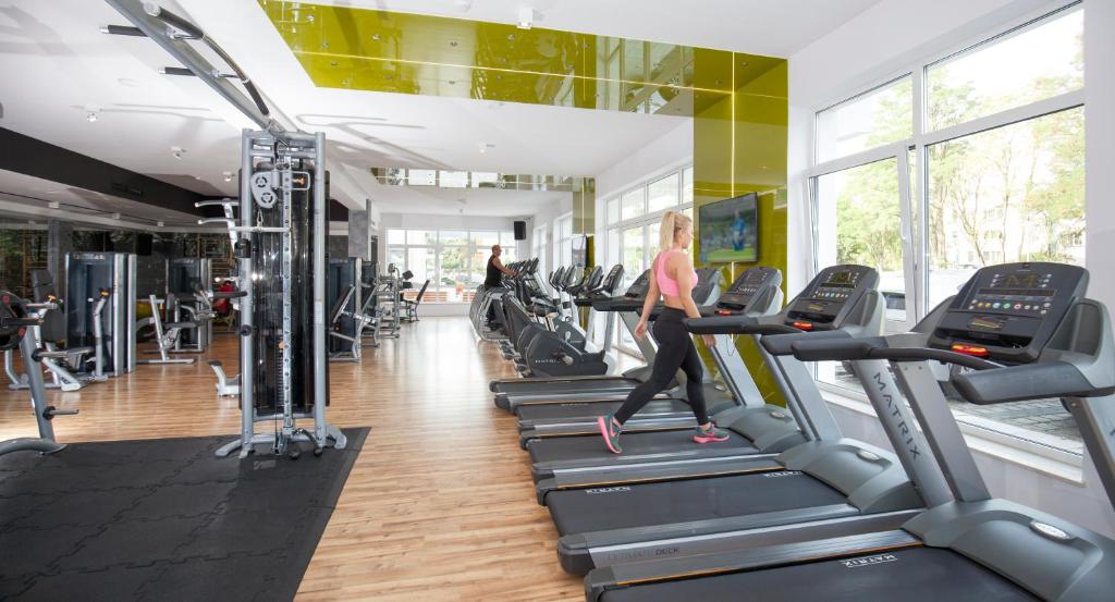 a woman running on treadmills in a gym at Grand Lubicz Uzdrowisko Ustka in Ustka