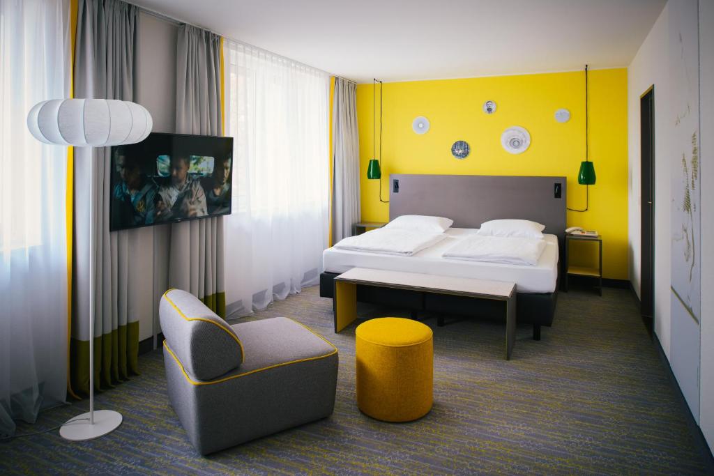 ein Hotelzimmer mit einem Bett und einem Stuhl in der Unterkunft Vienna House Easy by Wyndham Bad Oeynhausen in Bad Oeynhausen