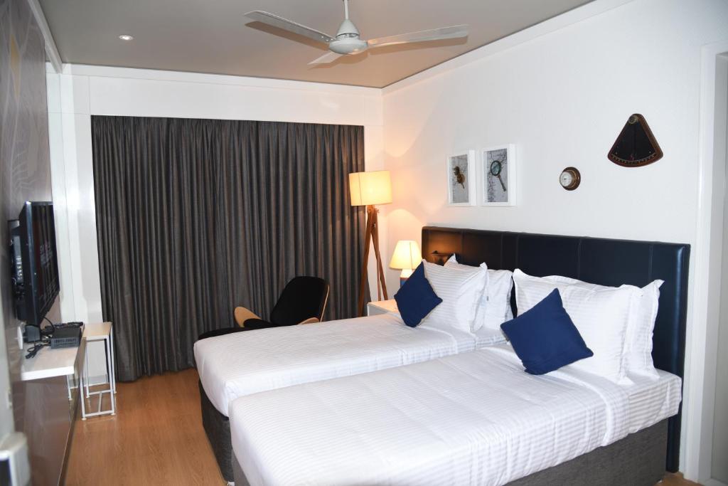 um quarto de hotel com duas camas com almofadas azuis em The Port Hotel em Visakhapatnam