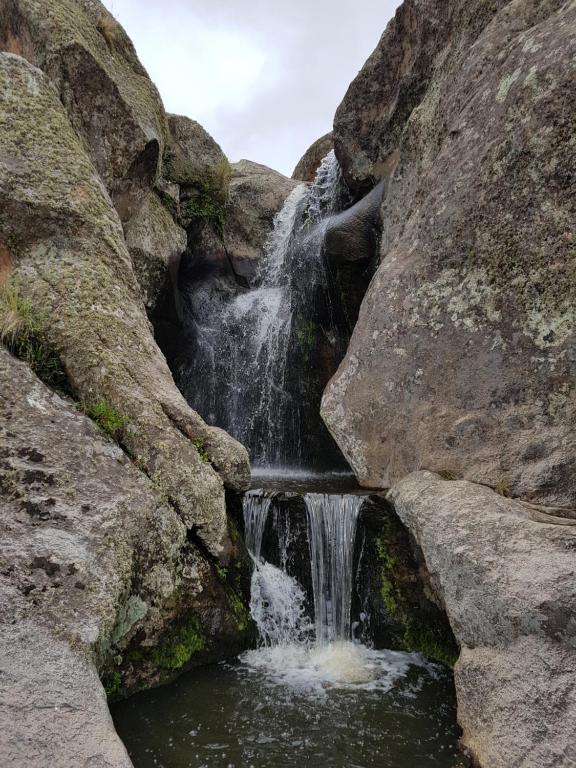 ein Wasserfall in der Mitte einiger Felsen in der Unterkunft La Posta Hotel y refugio De Montana in Mina Clavero