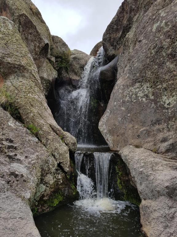 uma cascata no meio de algumas rochas em La Posta Hotel y refugio De Montana em Mina Clavero