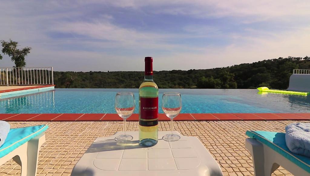 a bottle of wine sitting on a table with two glasses at Monte da Ameira in Roncão