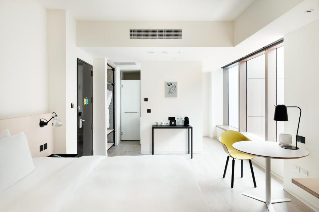 a white living room with a table and yellow chairs at amba Taipei Songshan in Taipei