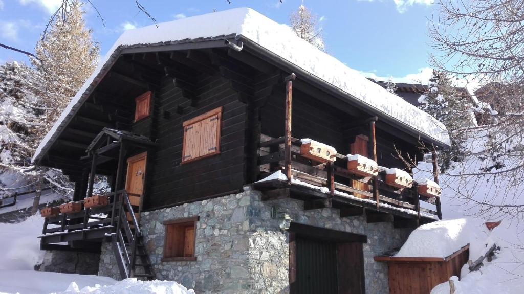 une cabane en rondins avec de la neige sur le toit dans l'établissement Chalet des Mélèzes, à Pila