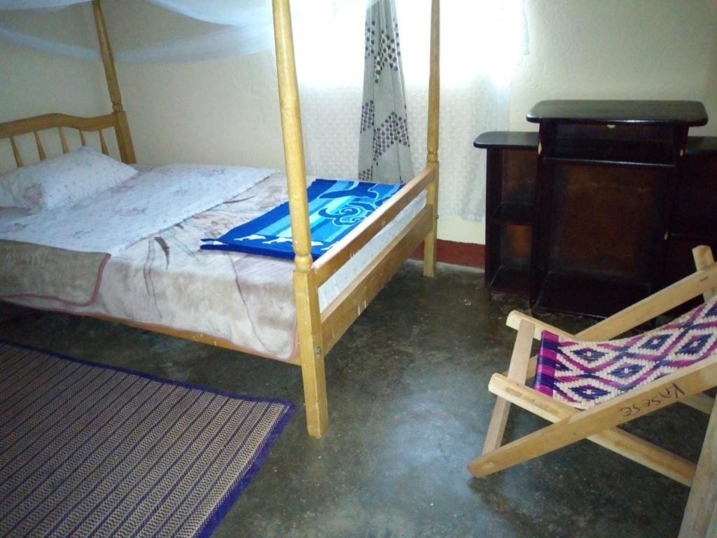 Rwenzori Trekking Homestay في Nyakalengija: غرفة نوم بسرير وكرسي ومكتب