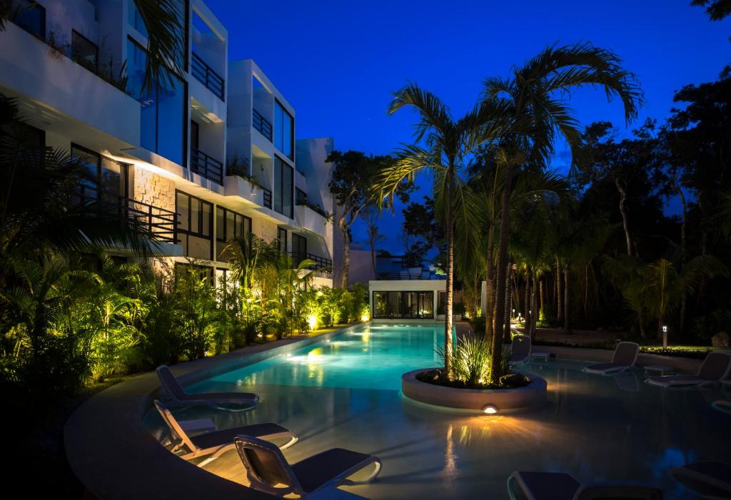 a swimming pool at night with chairs and a palm tree at Anah Suites Tulum by Sunest in Akumal