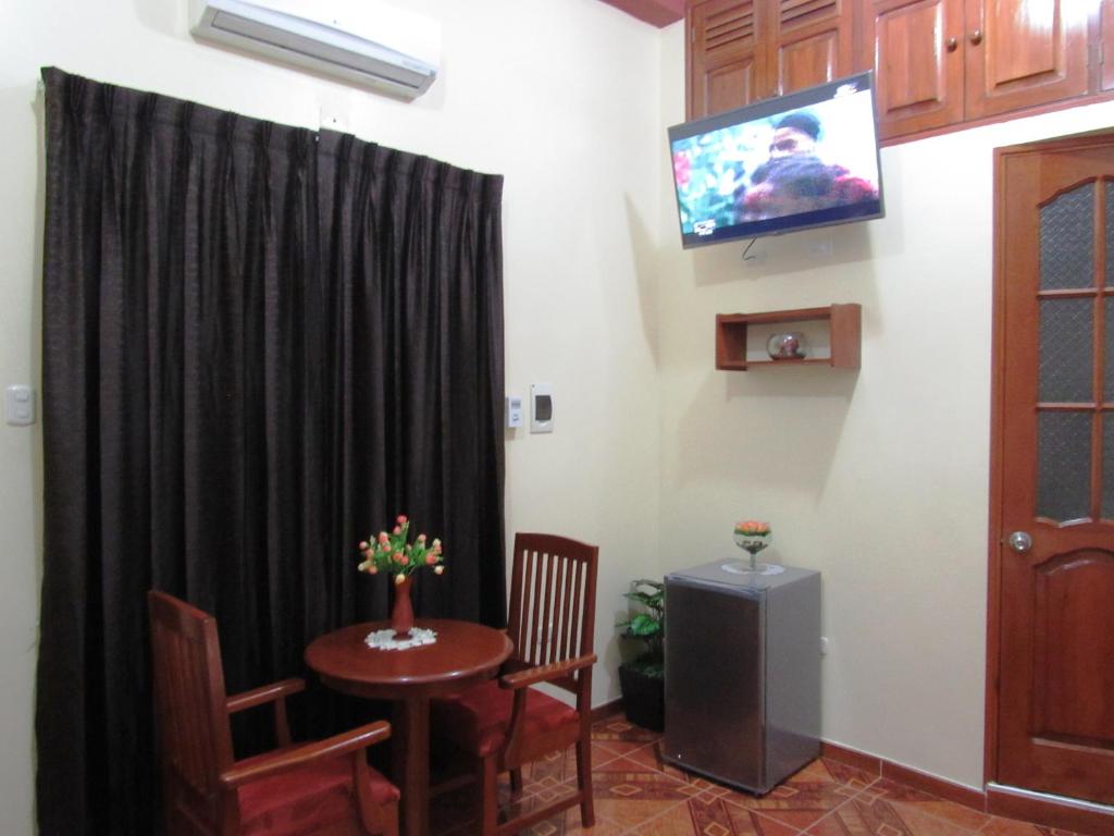 a room with a table and a television on a wall at Alojamiento El Cardenal in Iquitos