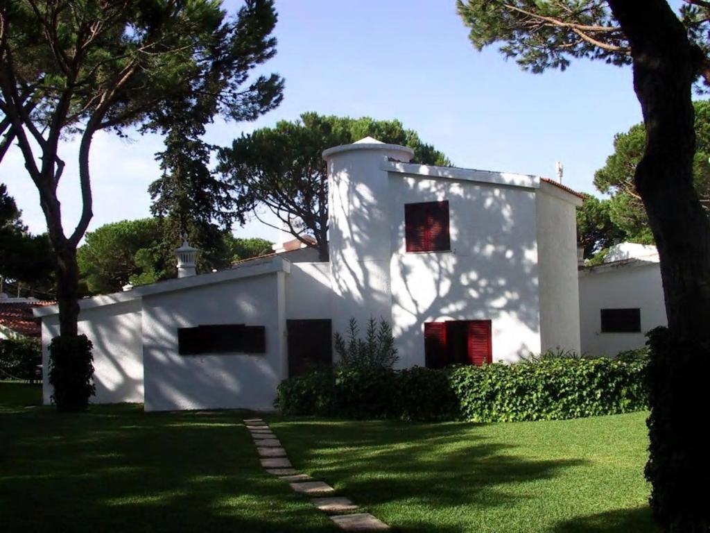 a white house with red windows in a yard at House with beautiful garden and swimming pool in Quarteira