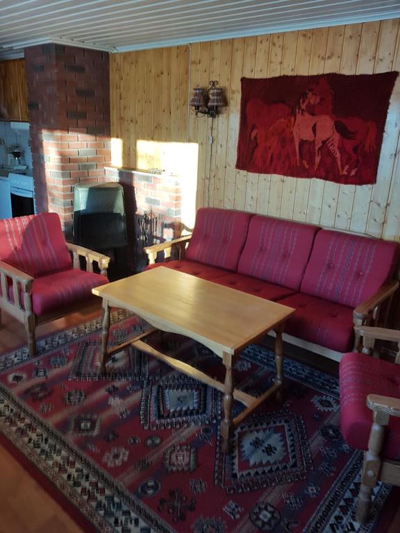 Knutebu Two-Bedroom Cottage في جيلو: غرفة معيشة مع أريكة حمراء وطاولة