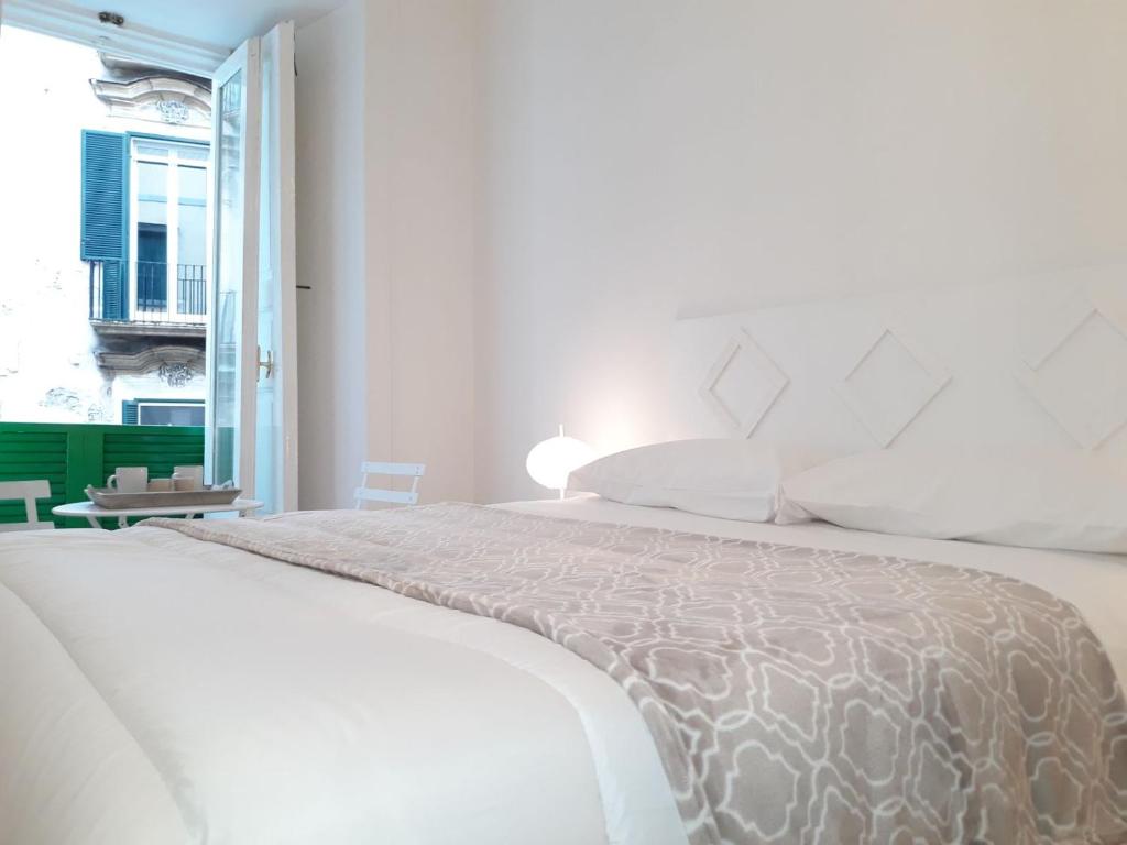 ein weißes Schlafzimmer mit einem großen Bett und einem Fenster in der Unterkunft Anna Home in Chiaia in Neapel