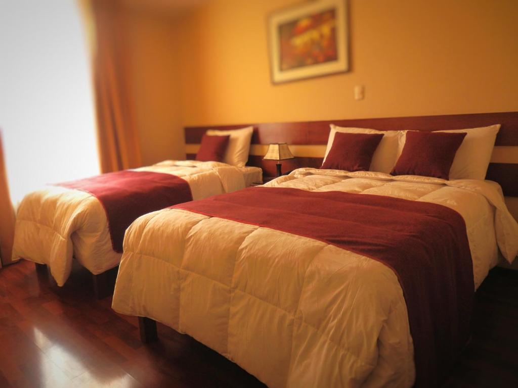 a hotel room with two beds and two lamps at Bella AQP in Arequipa