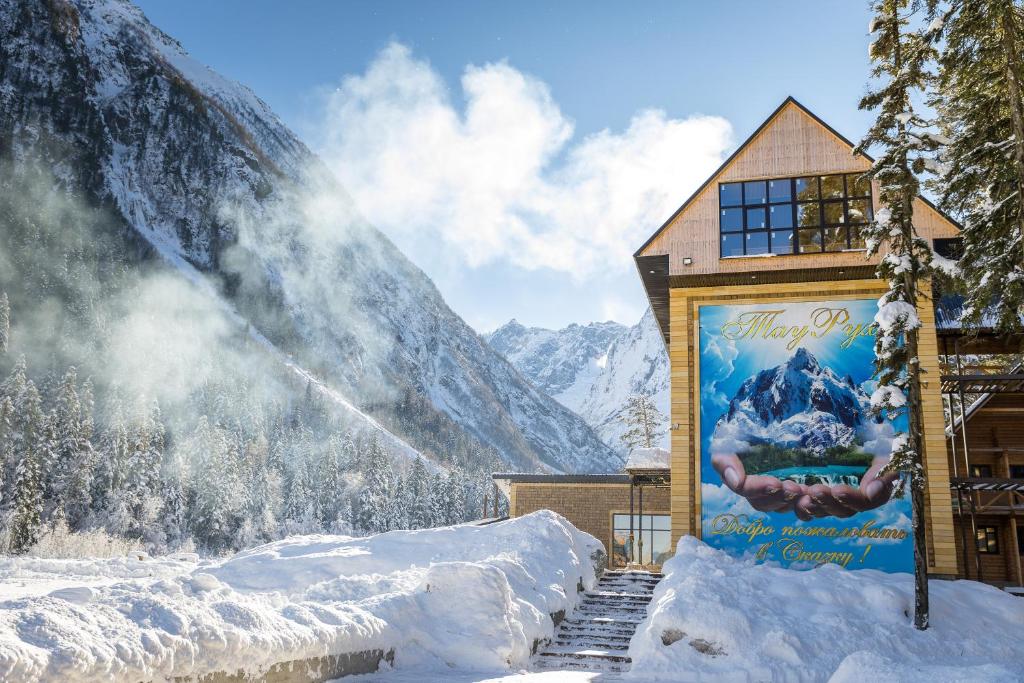 a building in the snow with a snow covered mountain at Hotel Tauruh in Dombay