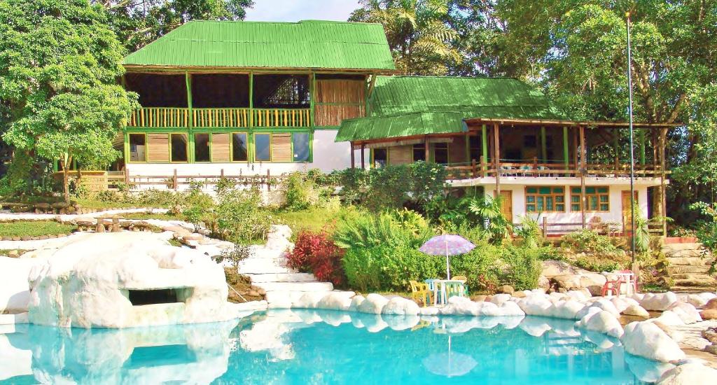 a house with a swimming pool in front of a house at Hosteria El Paraiso de las Orquideas in Archidona