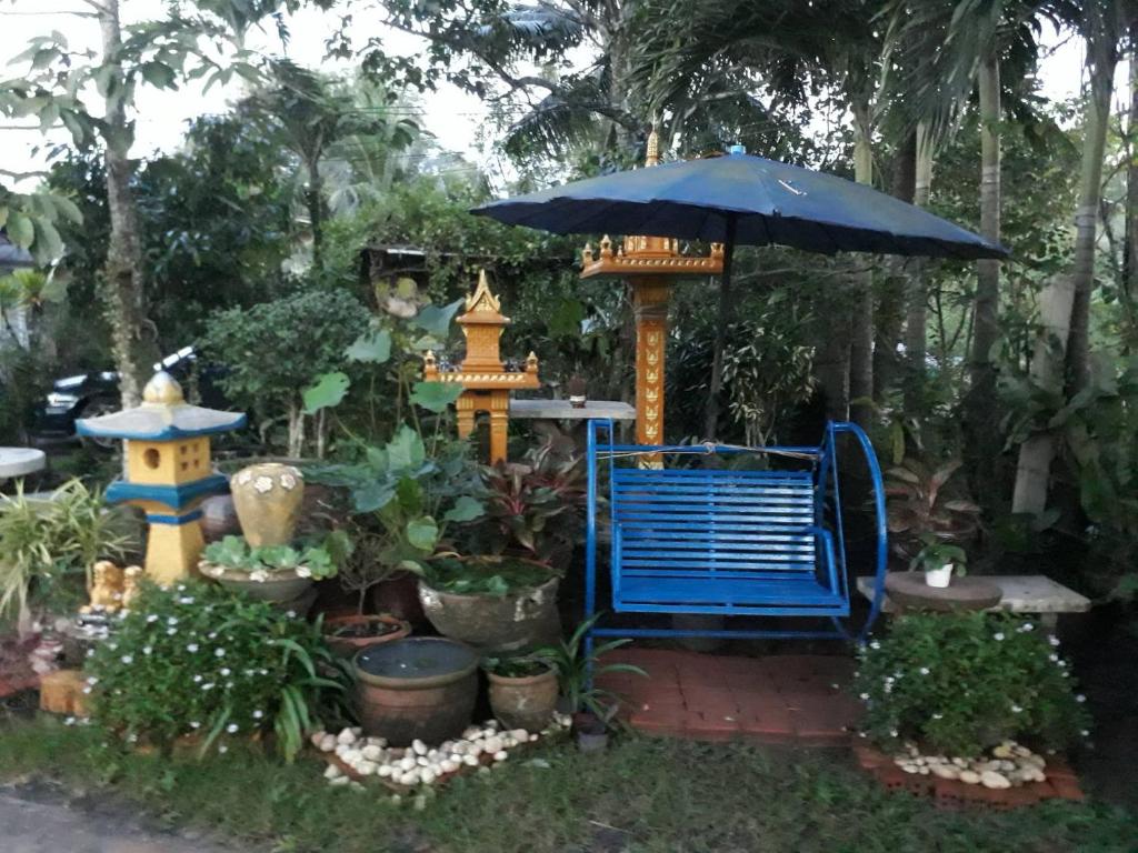 Una silla azul y una sombrilla en un jardín. en Garden Homestay, en Suratthani
