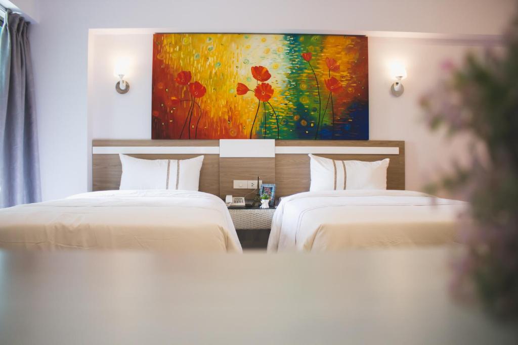two beds in a hotel room with a painting at Maverick Ratchada Hotel in Bangkok