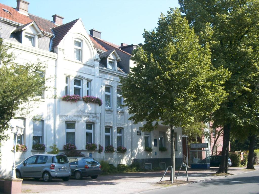 un edificio blanco con coches estacionados frente a él en Hotel Kaufhold - Haus der Handweberei, en Waltrop