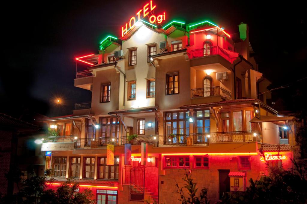 a lit up building with a neon sign on it at Family Hotel Ogi in Asenovgrad