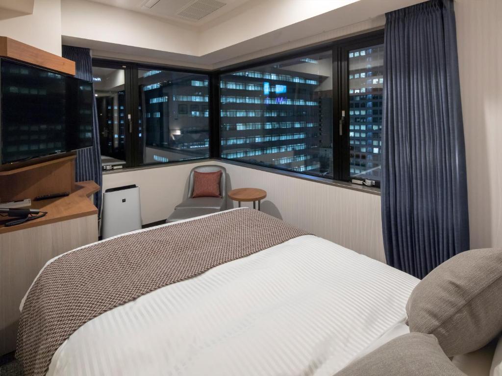 Schlafzimmer mit einem Bett und Stadtblick in der Unterkunft HOTEL MYSTAYS Midosuji Honmachi in Osaka