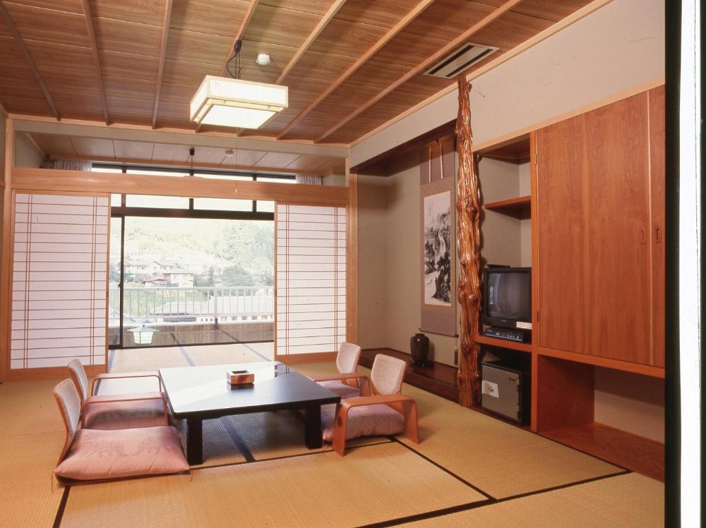 sala de estar con mesa, sillas y TV en Yuttarino-Sato Inaka en Achi