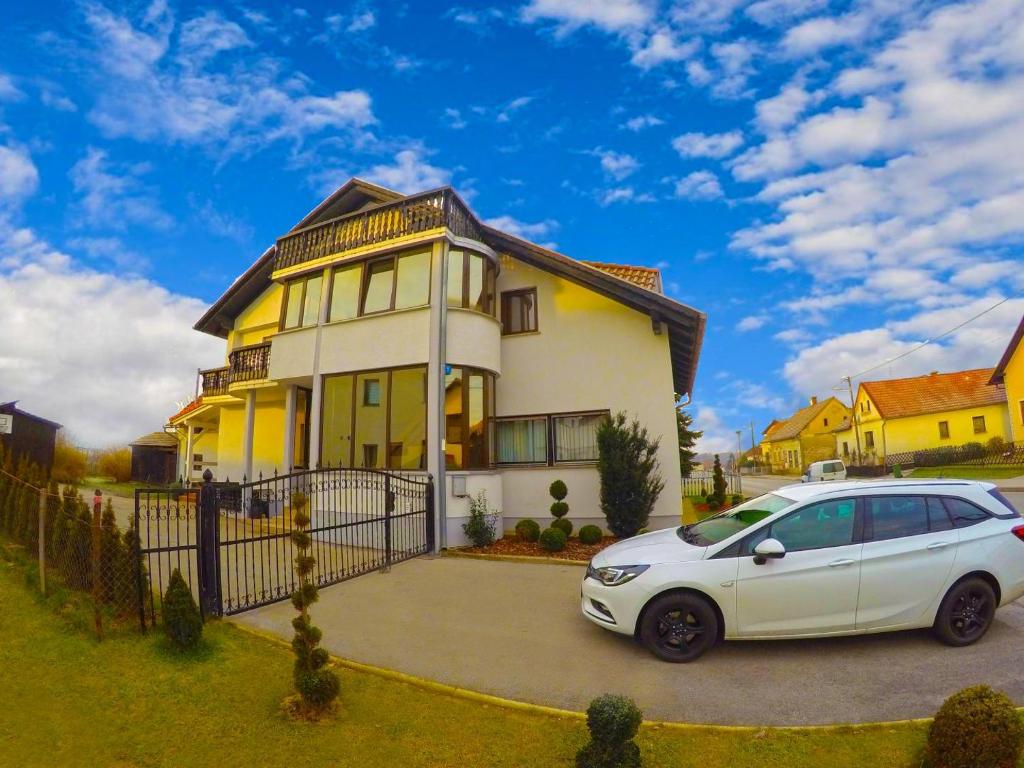 スヴェティ・マルティン・ナ・ムリにあるApartmani Oletić 4*の黄色い家の前に駐車した白車