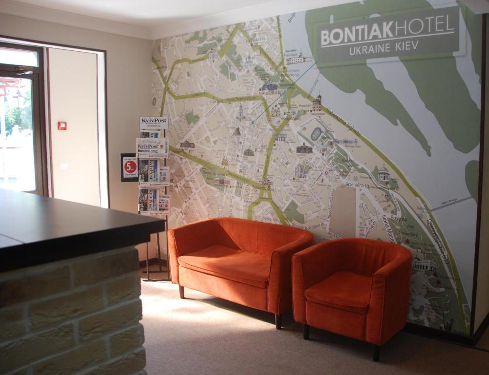a lobby with two orange chairs and a map at Bontiak Hotel in Kyiv