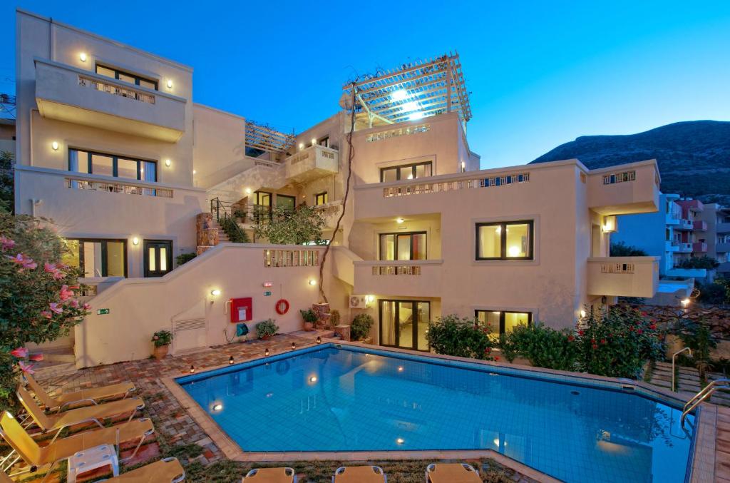 Villa con piscina frente a un edificio en Villiana Holiday Apartments, en Stalida