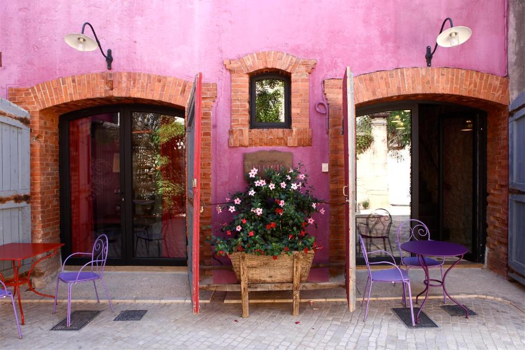 un edificio rosa con sillas y una planta frente a él en Village Castigno - Wine Hotel & Resort en Assignan
